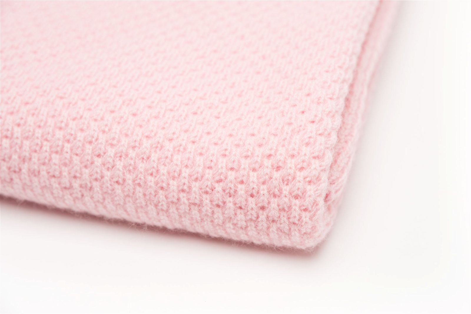 Close-up of a folded Nivas Cashmere Blend Baby Blanket in pink on a white background.