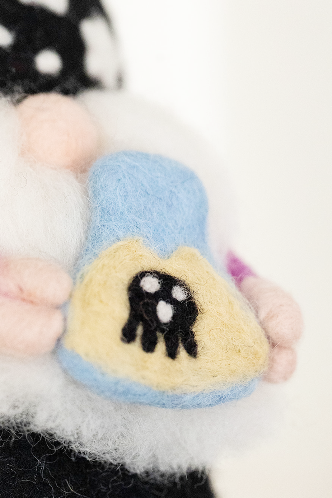 Close-up of the Nivas Halloween Gnome - Wizard figurine holding a blue and yellow object with a cow design, set against a blurred background—ideal for adding whimsical charm to your Halloween décor.